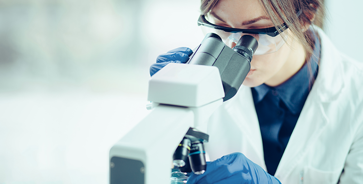 Women looking through light microscopy, in lab coat