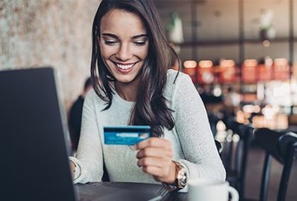 Woman looking at credit card while booking travel online.
