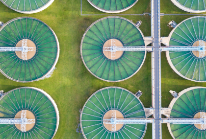 Aerial view of six circular water treatment basins with green interiors