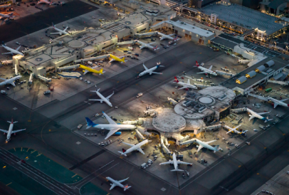 Night aerial photograph of airport terminal with illuminated gates and multiple planes parked