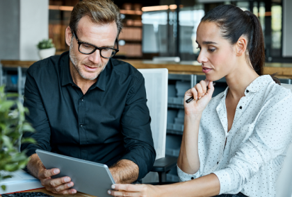 Two colleagues discussing content on a tablet in a bright modern office space.