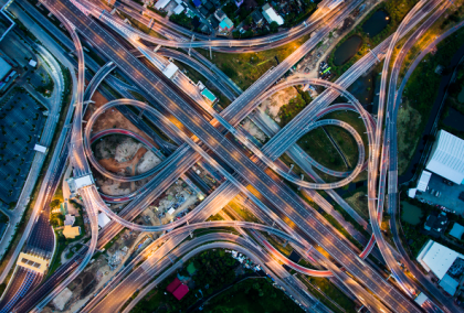 Aerial night view of illuminated cloverleaf highway interchange with car light trails