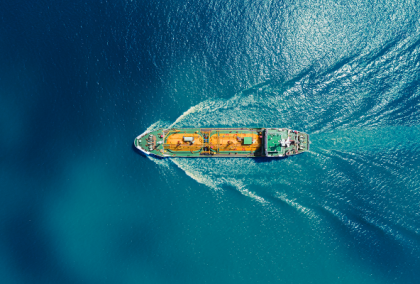Aerial view of a green cargo ship sailing across deep blue water