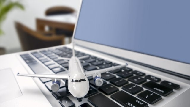 Modelo de avión sobre una computadora portátil que representa la gestión estratégica de viajes corporativos basada en datos y tecnología.