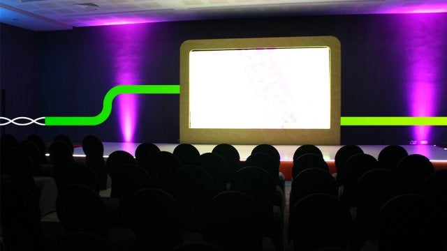 Escenario preparado para lanzamiento de producto en evento corporativo con iluminación y pantalla central