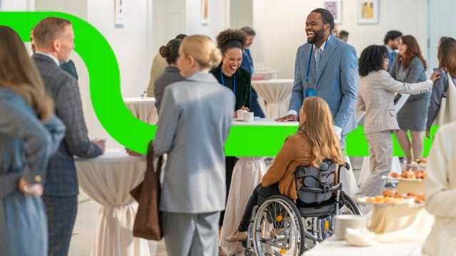Profesionales interactúan durante un evento corporativo inclusivo, fomentando la participación y las conexiones entre asistentes de diferentes perfiles. 