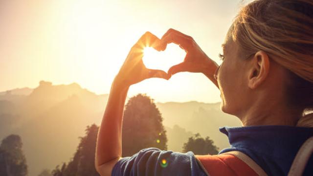 women with heart hands in the sun