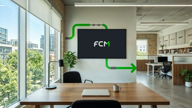 Modern office with a wall-mounted TV displaying "FCM" and green graphic elements.