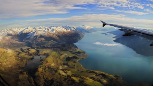 Plane wing over top of mountains 