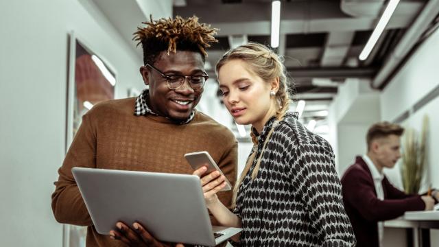 Young black man and a young blonde woman look at information on a laptop while at work