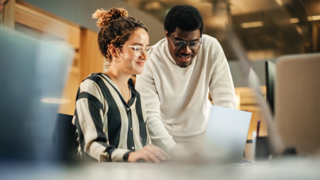 Woman and man collaborating over a laptop in a bright modern office