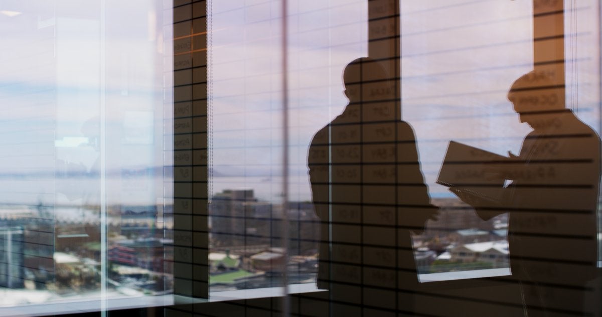 Ejecutiva observando la ciudad desde un edificio corporativo mientras analiza decisiones estratégicas para el negocio.