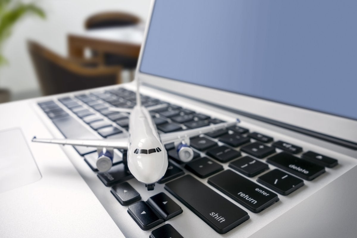 Modelo de avión sobre una computadora portátil que representa la gestión estratégica de viajes corporativos basada en datos y tecnología.