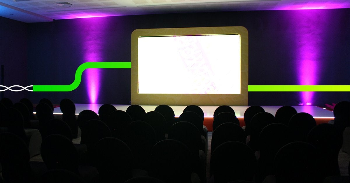 Escenario preparado para lanzamiento de producto en evento corporativo con iluminación y pantalla central