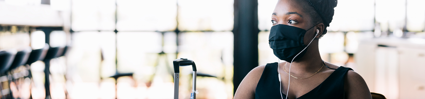 Business traveller with mask waiting at airport