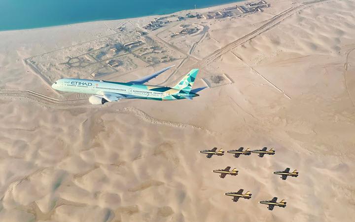 Eithad aircraft flies over the desert with 6 fighter jets flying below