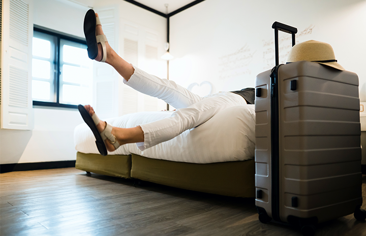 Woman jumping onto bed after long flight.