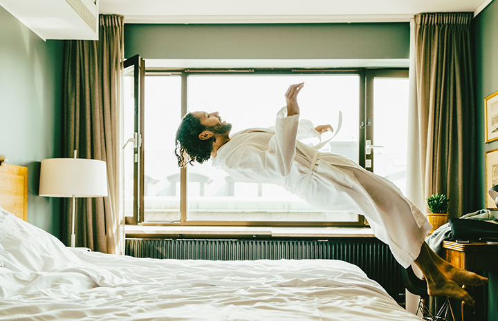Man in robe jumping onto bed