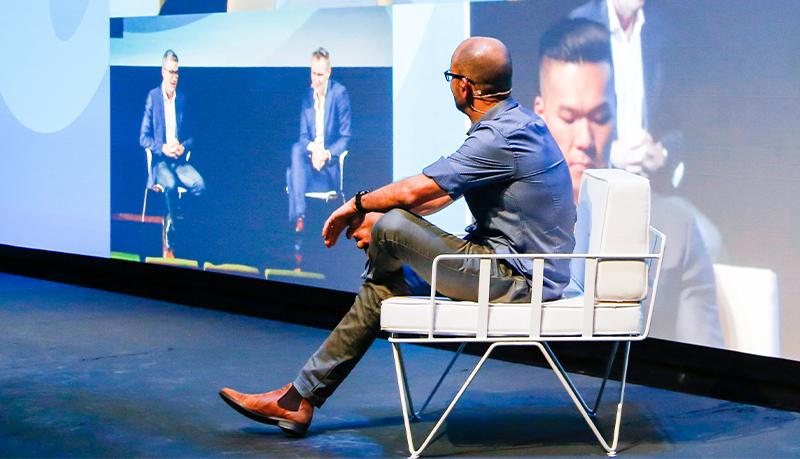 Man sitting on stage in front of screen