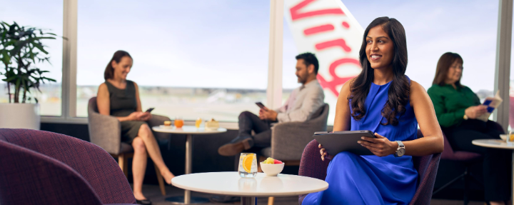 A business traveller sits in the Virgin Australia lounge using her tablet