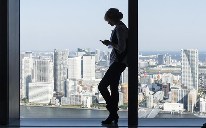 Women standing next to window looking at her phone