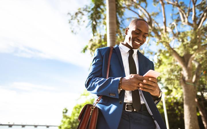 Man in a blue suit smiling at his phone 