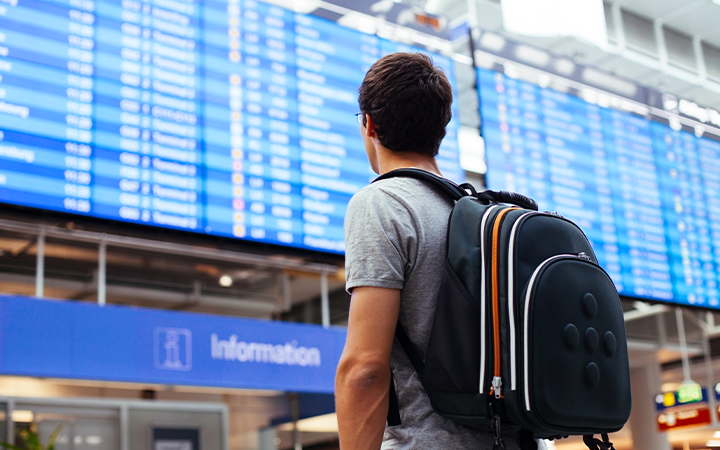 man in an airport looking at plane schedule