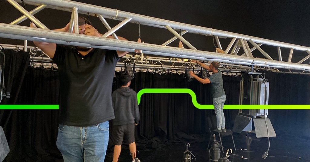 Equipo técnico instalando estructura, iluminación y producción audiovisual para un evento corporativo antes de su ejecución.