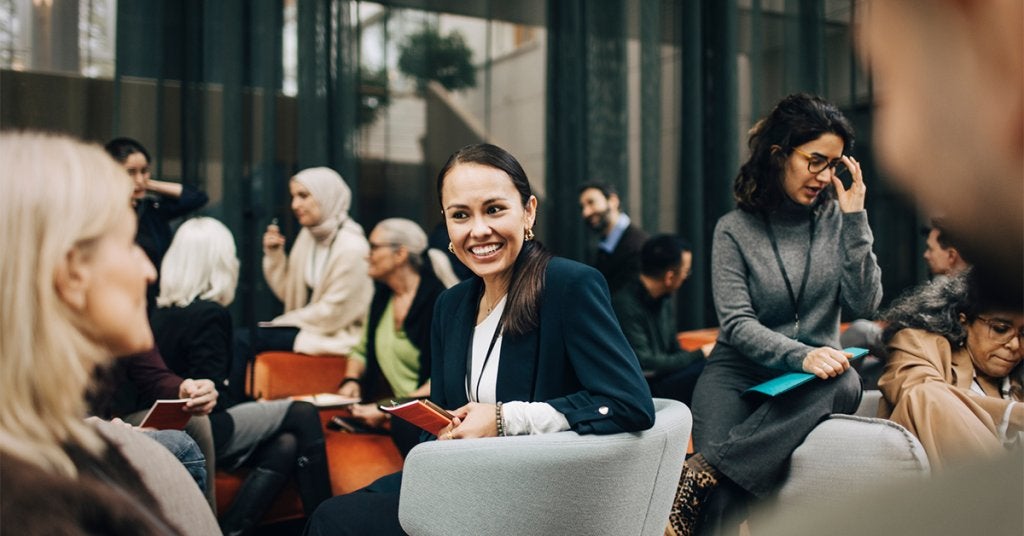 Profesionales interactúan durante un evento corporativo inclusivo, fomentando la participación y las conexiones entre asistentes de diferentes perfiles. 