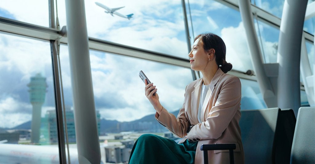 Ejecutiva observando un avión mientras revisa su itinerario por viaje de negocios.