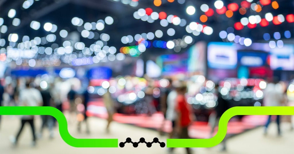 Asistentes caminando en evento corporativo con iluminación dinámica y ambiente profesional.