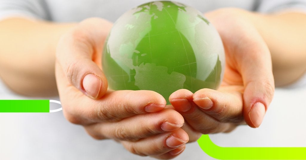 Manos sosteniendo una esfera verde que representa el planeta y el compromiso empresarial con la sostenibilidad.
