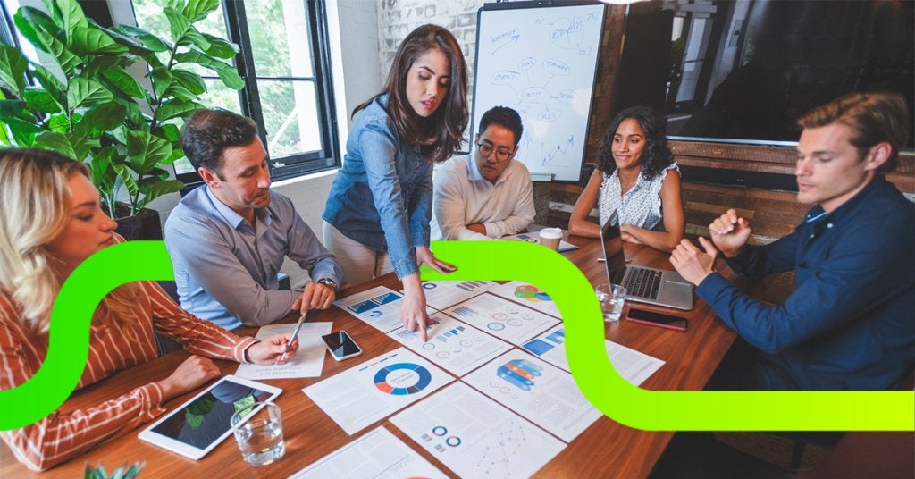 Equipo ejecutivo revisando gráficos impresos y reportes financieros en mesa de juntas, reflejando toma de decisiones basada en datos y medición de ROI en eventos corporativos.