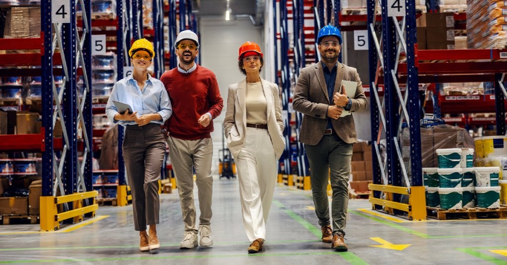 Equipo de profesionales recorre un centro de distribución durante una visita de negocio.