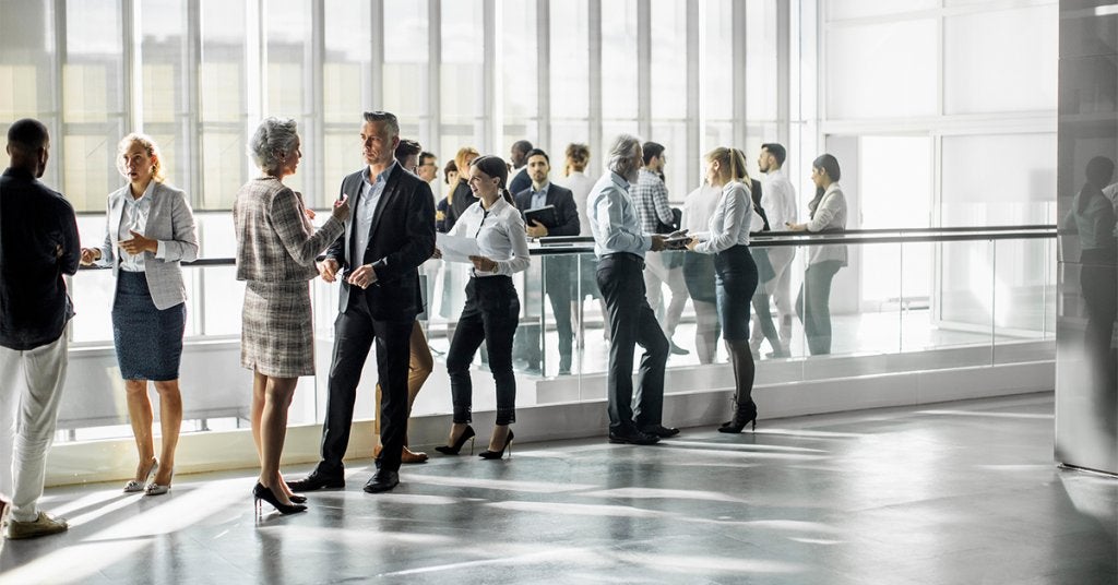 Ejecutivos conversan y generan conexiones profesionales durante una sesión de networking en un entorno corporativo.