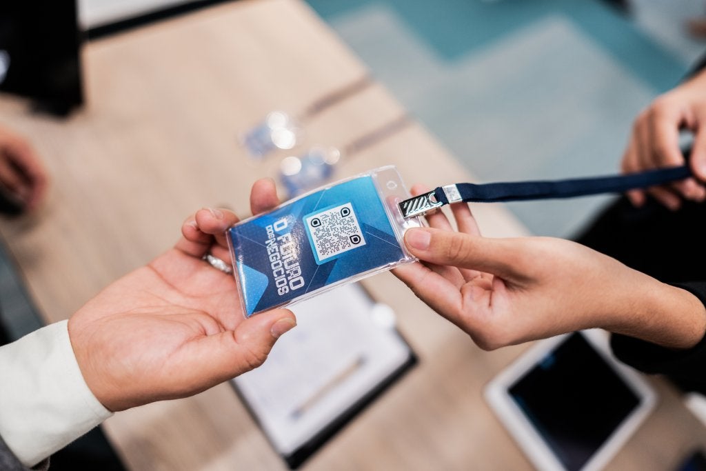 Entrega de gafete con código QR durante un evento de negocios, representando la captura de datos y trazabilidad en los viajes corporativos.