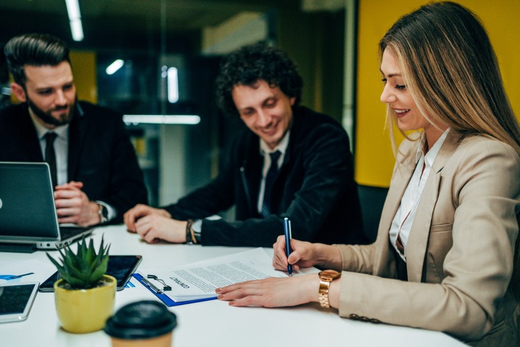 Profesional formalizando decisiones de negocio durante una reunión de trabajo enfocada en la gestión y optimización de recursos.