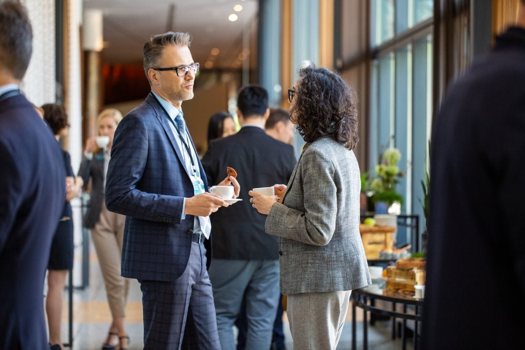Asistentes conversando durante una sesión de networking en un evento corporativo presencial.