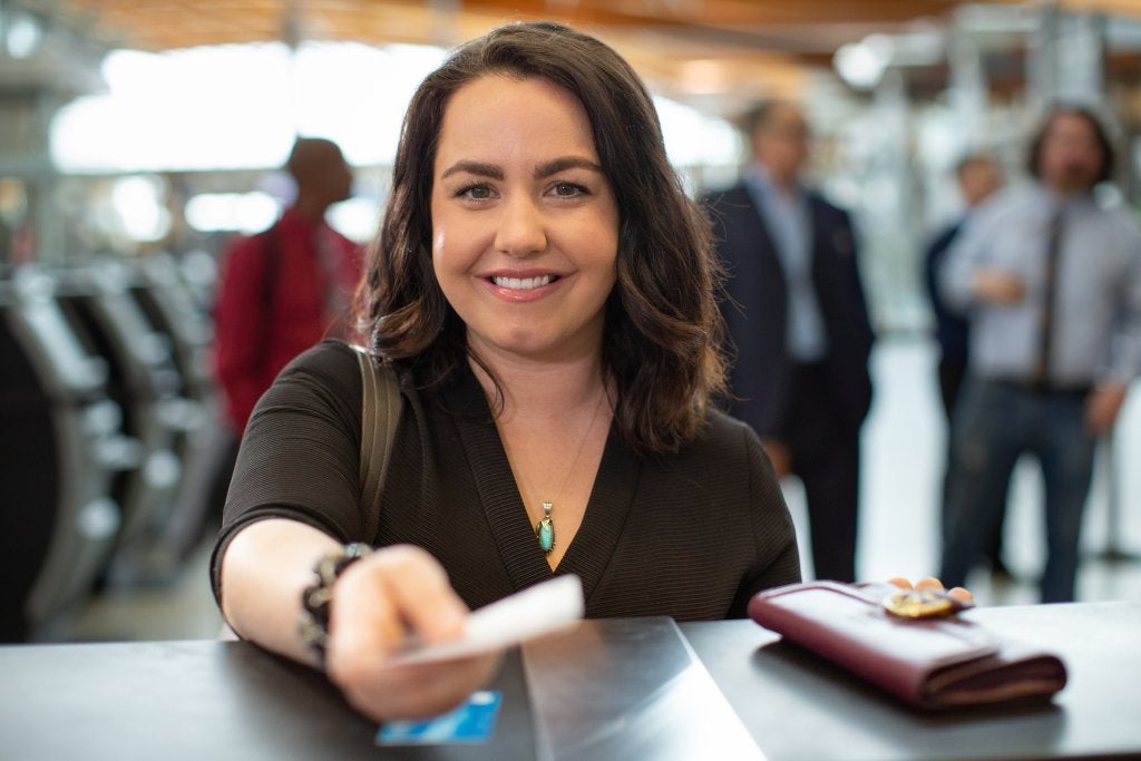 Viajera corporativa realizando un proceso de registro en aeropuerto antes de iniciar un viaje de negocios.