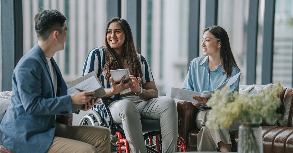 Asistente con movilidad reducida es recibido durante el proceso de registro de un evento, en un espacio diseñado para facilitar el acceso y la participación.