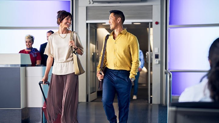 Two travellers exiting an airbridge looking and smiling at each other