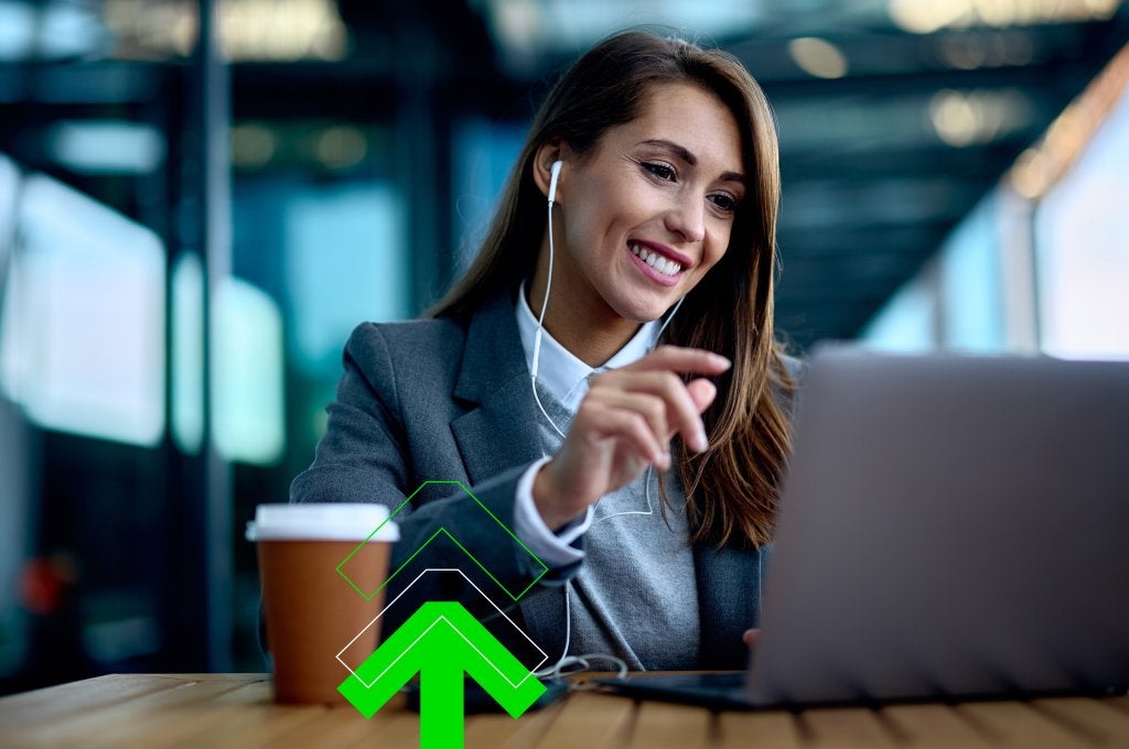 Executive woman at the airport with a coffee and smiling at laptop