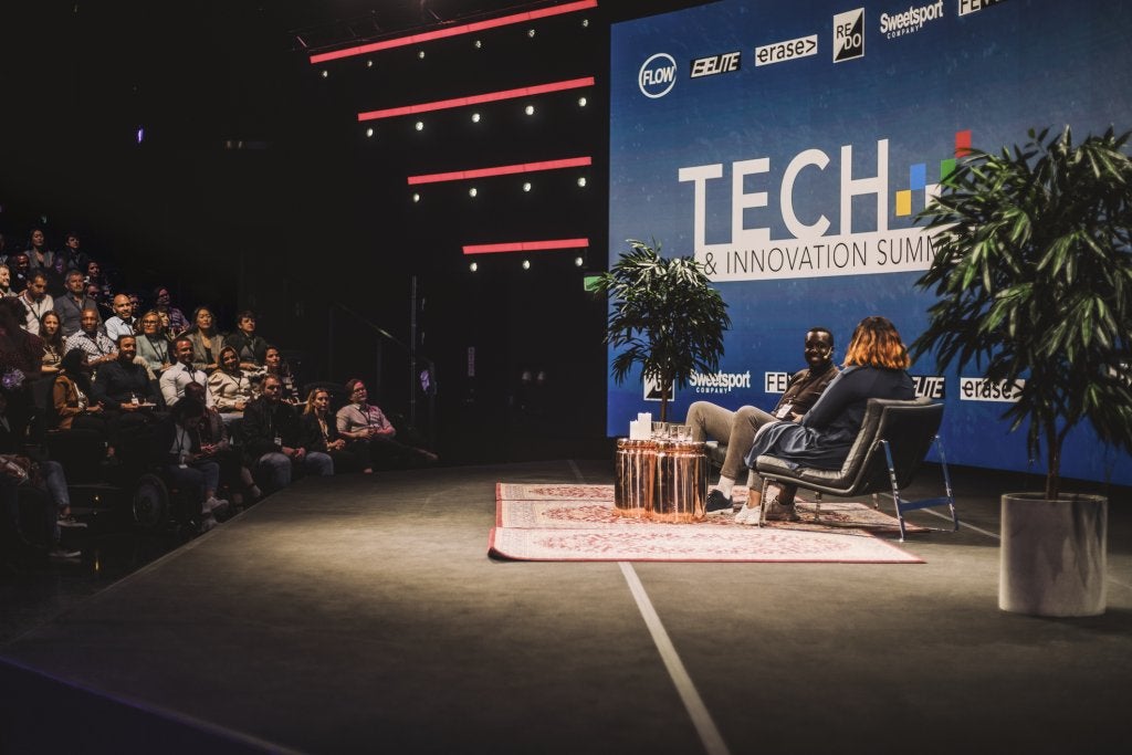 Businessman listening to female interviewer by audience at convention center.