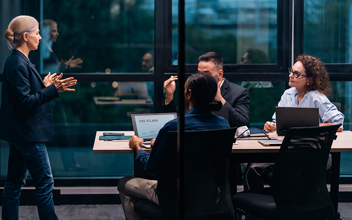 A diverse team in a modern conference room discusses a project, focused and engaged.