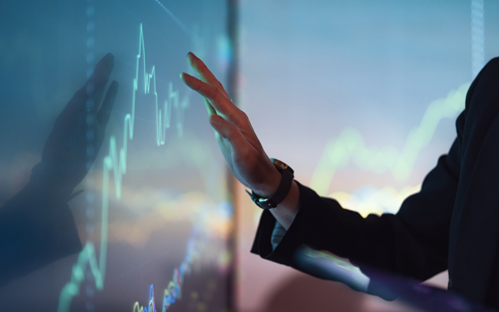 A business professional gestures towards a digital graph displaying financial data.