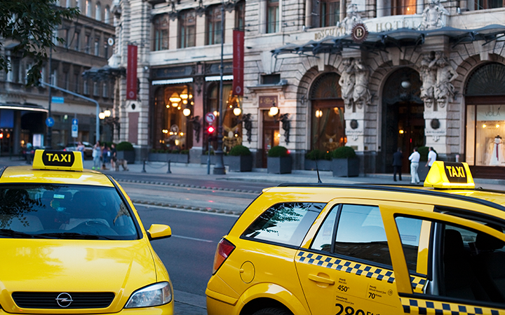 Two yellow taxis parked near a historic building with an elegant facade.