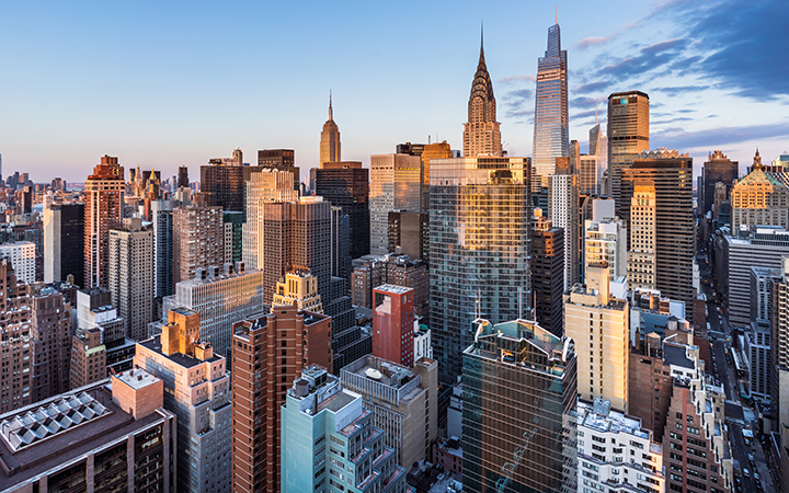 Photograph of Manhattan skyline at sunset with golden light and scattered clouds