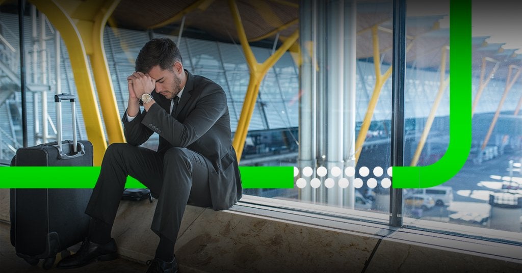 Ejecutivo con signos de fatiga en un aeropuerto, reflejando el impacto del cansancio y la sobrecarga mental en los viajes corporativos frecuentes.