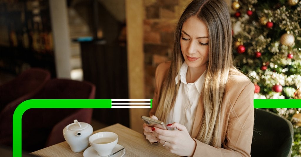 Mujer de negocios trabajando desde una cafetería decorada para Navidad, simbolizando la importancia del bienestar y la experiencia del viajero.