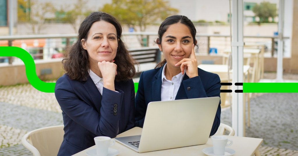 Dos mujeres de negocios trabajando en una laptop durante una reunión, representando la planeación estratégica para modernizar políticas de viaje.